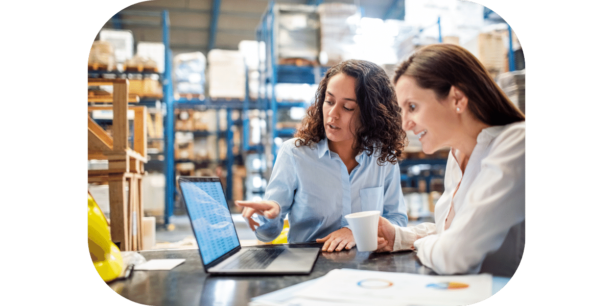 Two ladies meeting in a warehouse around a computer